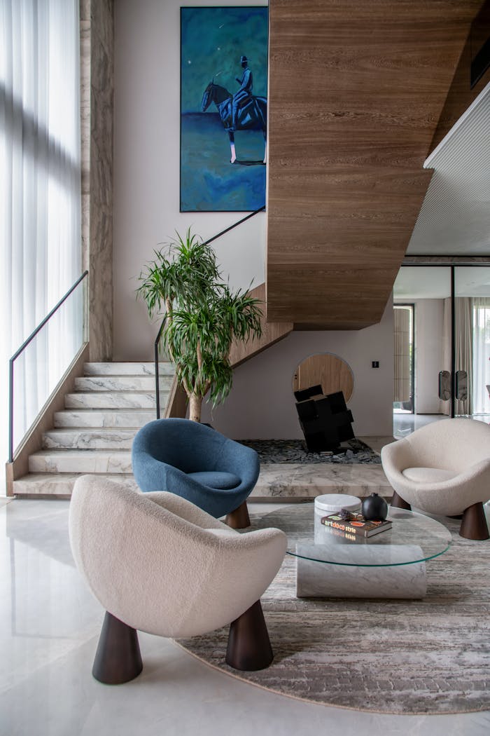 About Elegant modern living room featuring unique chairs, art, and staircase for luxury appeal.